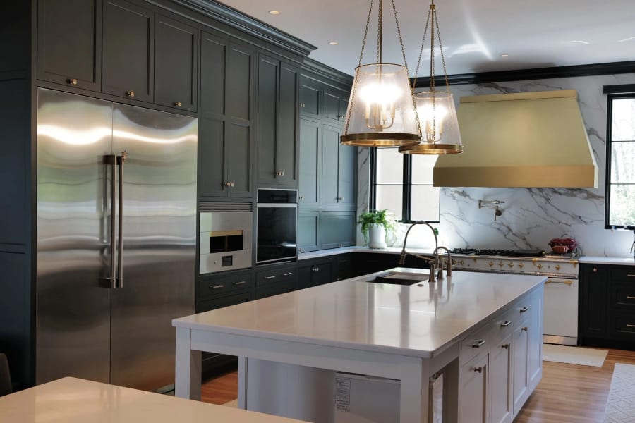 Silverwood luxury kitchen with dark cabinetry marble backsplash brass hood and pendant lights